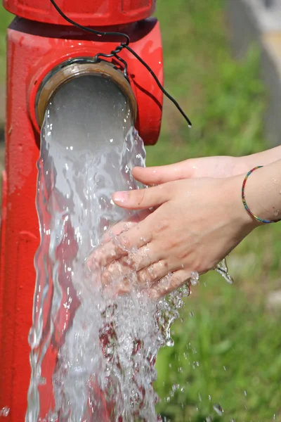 Wash hands under the powerful jet of water from a fire hydrant — Stock Photo, Image