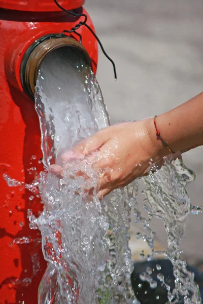 Wash hands under the powerful jet of water from a fire hydrant — Stock Photo, Image