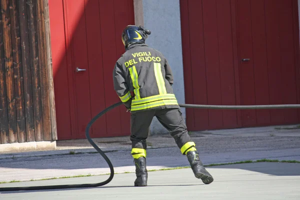 Bombero en acción durante un incendio con la manguera de agua —  Fotos de Stock