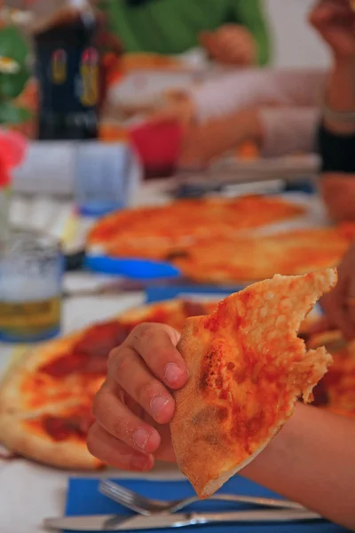 Familia feliz alrededor de la mesa mientras come sabrosa pizza — Foto de Stock