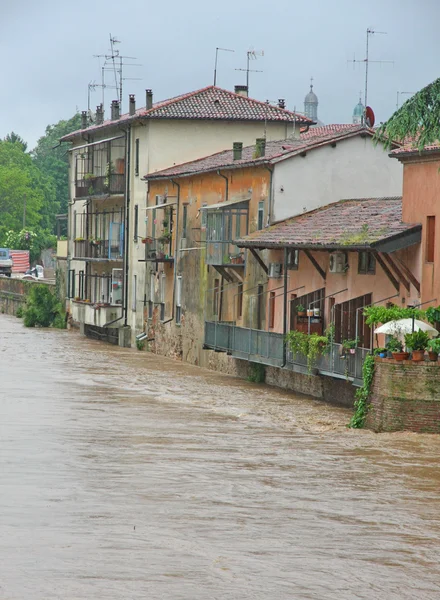 Case vicino alla riva del fiume infuria durante il diluvio — Foto Stock