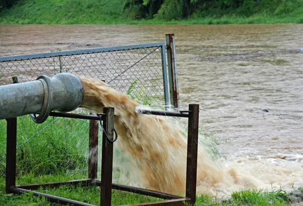 Giant exhaust pipe pours into the muddy and Brown slurry — Stock Photo, Image