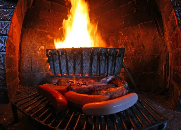 Kominek ogień oświetlone i grilla mięso — Zdjęcie stockowe