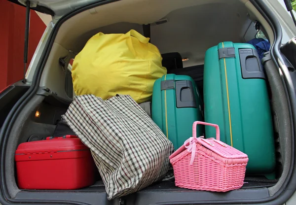 Dos maleta verde y una bolsa de basura rosa en el maletero de la fami —  Fotos de Stock