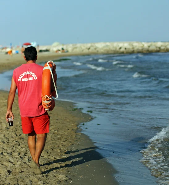 Bagnino sulla spiaggia con un bicchiere di soda e salvagente — Foto Stock