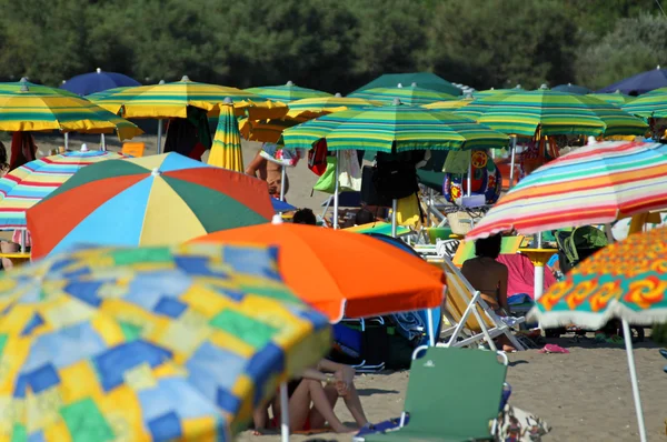 Umbrellas piled on the shores of the sea on the crowded beach — Stock Photo, Image