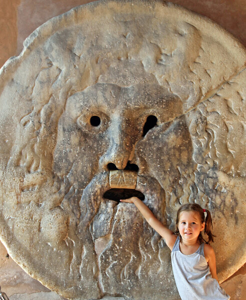 young girl puts her hand inside the mouth of truth in Rome italy