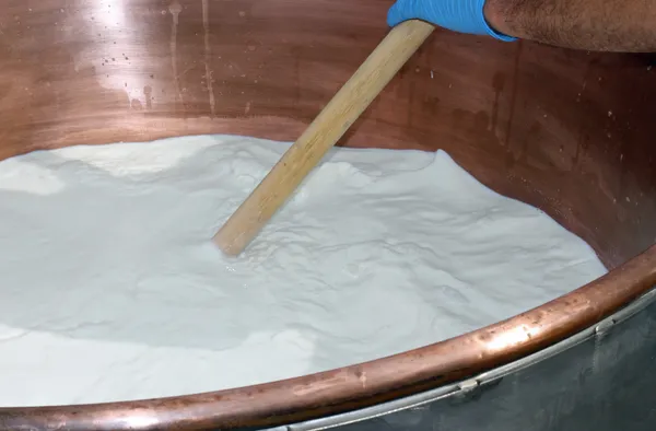 Працівник змішує молоко у великому котлі для приготування сиру — стокове фото