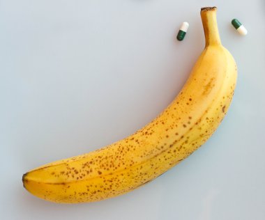 Yellow banana with two pills clipart
