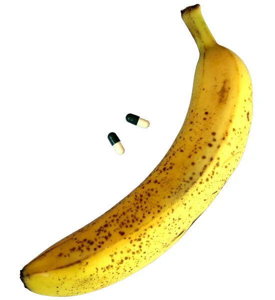 Желтый банан с двумя таблетками для мужских проблем — стоковое фото