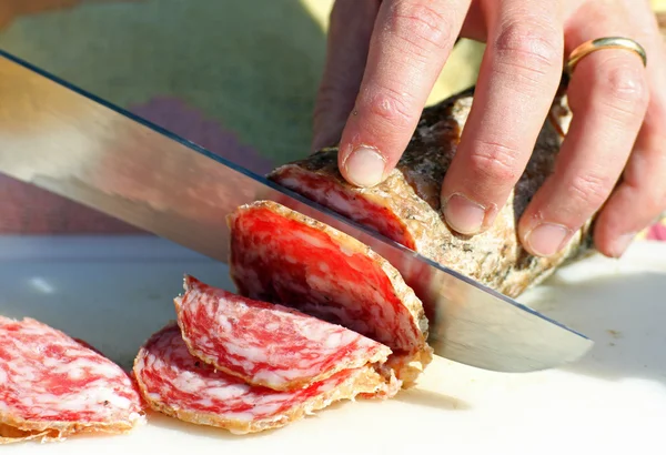 Salami sliced by butcher's hands — Stock Photo, Image