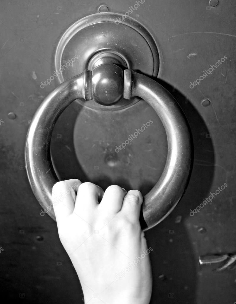 hand of a child who knocks on the door of an iron gate