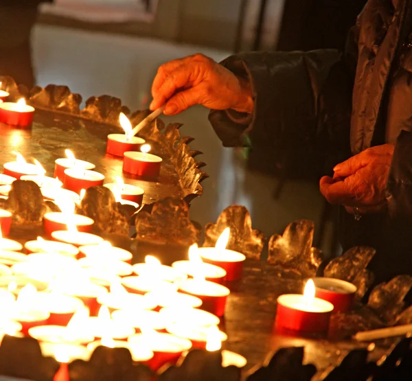 Mãos de uma mulher idosa acendendo uma vela — Fotografia de Stock