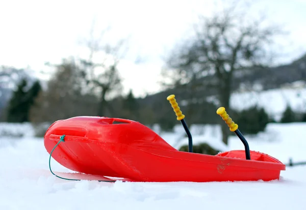 Bob vermelho feito de plástico robusto na neve na montanha — Fotografia de Stock