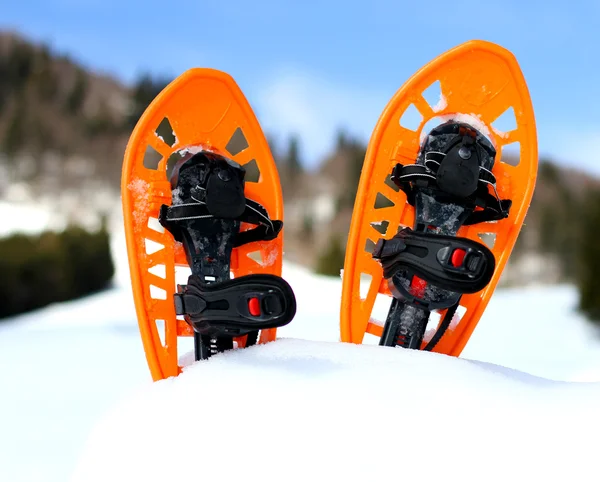 Naranja raquetas de nieve para caminar sobre la nieve blanca y el cielo azul —  Fotos de Stock