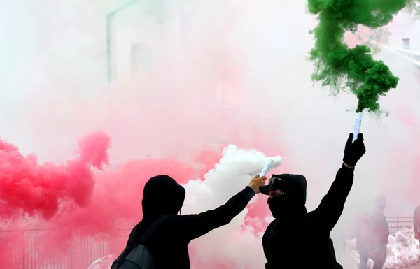 Ultras fans with smoke red white and green dressed in black — Stock Photo, Image