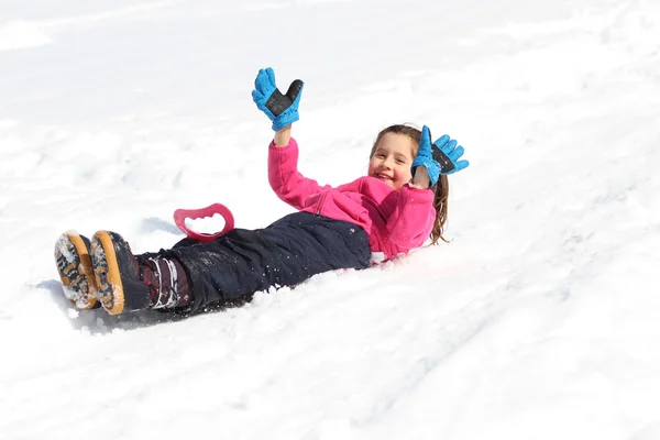 Nice little girl slips down on snowy mountain — Stock Photo, Image