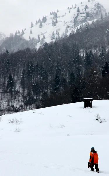Ung pojke går genom den vita snön i fjällen — Stockfoto