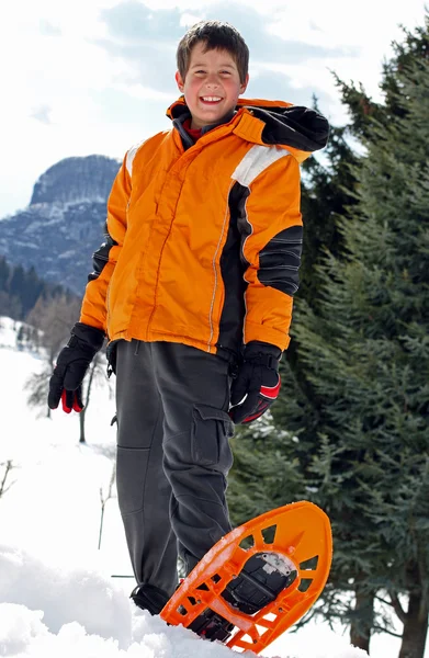 Menino com roupas de inverno e snowshoes para um longo passeio no sn — Fotografia de Stock