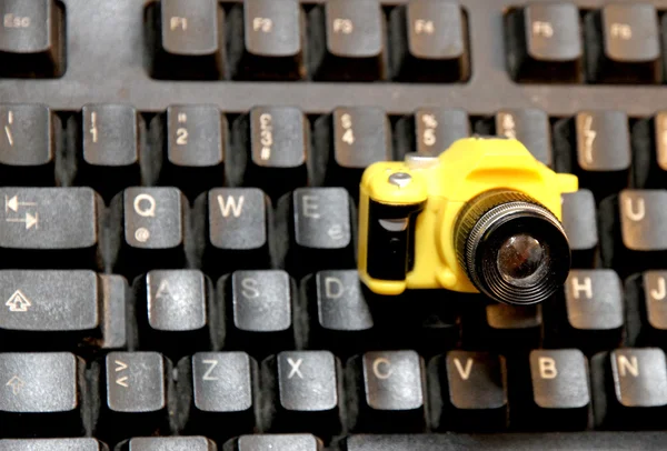 Teclado do computador e uma pequena câmera de brinquedo — Fotografia de Stock