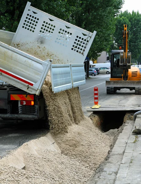 Ribaltabile camion durante lo svuotamento della strada sterrata durante il e — Foto Stock