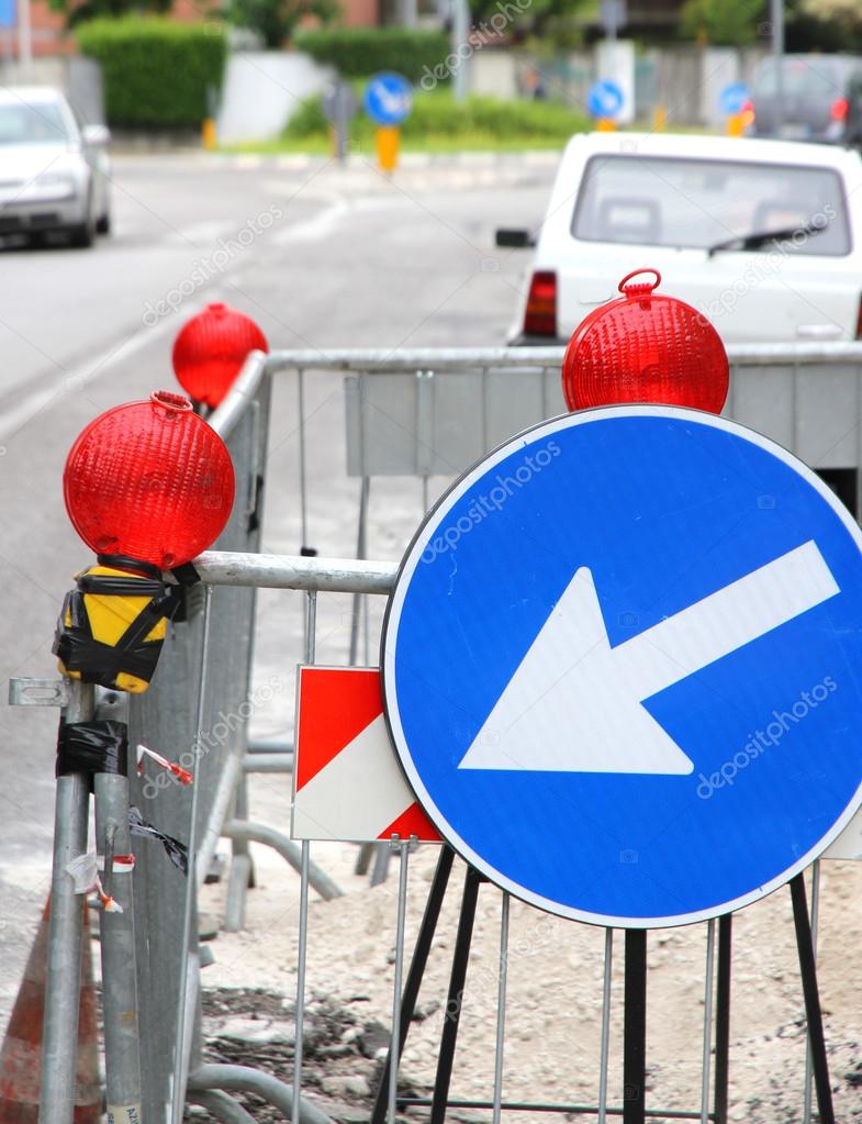 narrowing of the roadway with red signal lamps and a road sign t