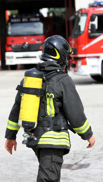 Πυροσβέστης με κύλινδρο κίτρινο οξυγόνου και το κράνος — Φωτογραφία Αρχείου