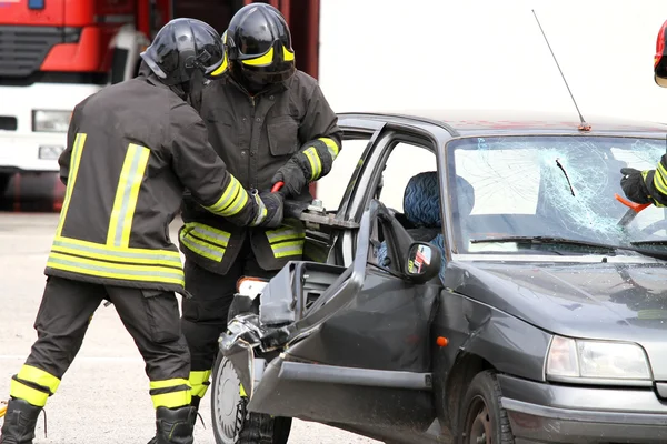 Пожарные с пневматическими ножницами открывают двери автомобиля — стоковое фото