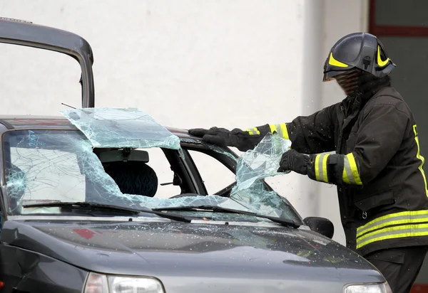 車のフロント ガラスを壊す一方で人々 を解放する消防士 — ストック写真