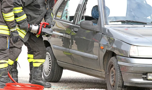 Firefighters with the pneumatic shears open the car doors after — Stock Photo, Image