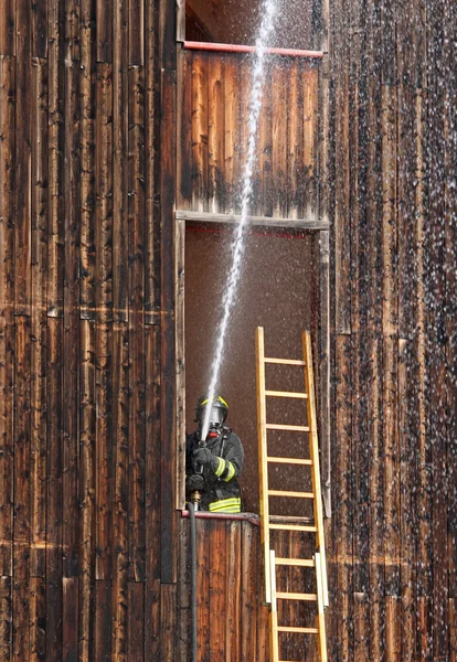 Hasič s hydrantu v akci při zhasínání ohně dur — Stock fotografie