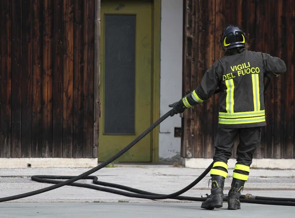 Italian fireman collects the water hose after turning off the fi — Stock Photo, Image