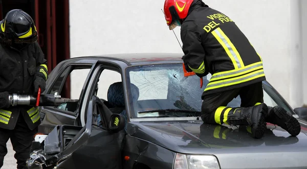 Bomberos en acción mientras abren el coche después del accidente —  Fotos de Stock