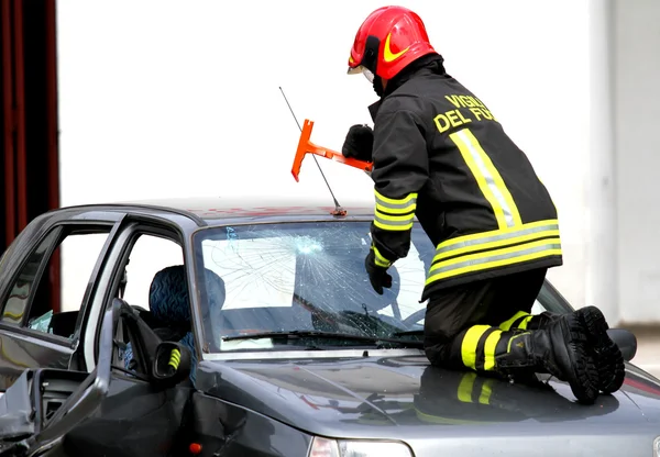 Jefe de bomberos rompe el parabrisas del coche con un martillo — Foto de Stock