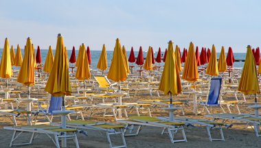 closed umbrellas and deckchairs on the beach at sunset on the se clipart