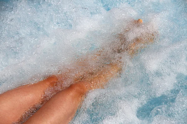 Mooie vrouwen benen in de badkuip met whirlpool met water om — Stockfoto