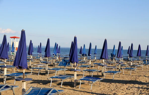 Sonnenschirme und Liegestühle am Strand bei Sonnenuntergang am Meer — Stockfoto