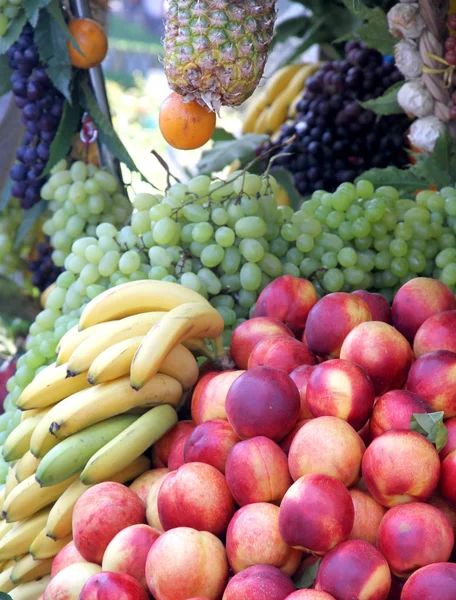 Банани та персики та інші фрукти для продажу на ринку — стокове фото