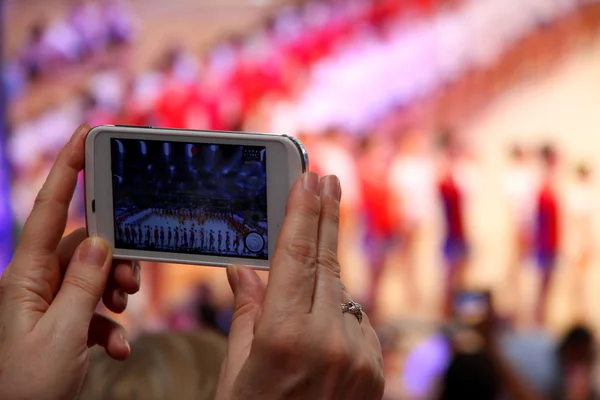 Mano della vecchia donna con il nuovo smartphone che prende uno spettacolo in un s — Foto Stock