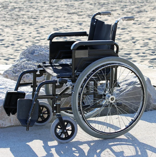 Silla de ruedas en la playa de arena junto al mar en verano — Foto de Stock
