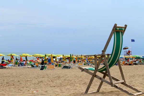 Sdraio in legno sulla spiaggia con ombrelloni in estate — Foto Stock