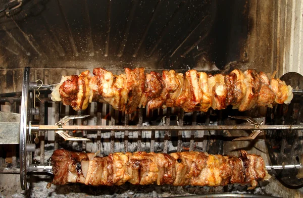 Espetos de carne cozidos para cuspir na lareira giratória — Fotografia de Stock