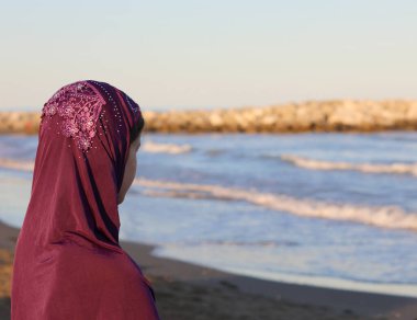 Yazın başını deniz kenarına örtecek Arap peçeli genç bir kız.