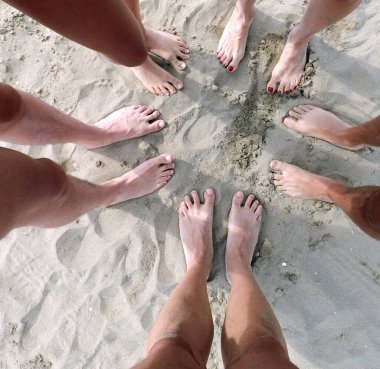 Beş kişilik bir aile, ayakları kumlu kumsalda bir çember içinde.