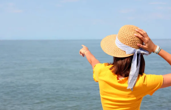 Młoda Dziewczyna Słomkowym Kapeluszu Wskazującym Dolny Punkt Horyzoncie Otwartym Morzu — Zdjęcie stockowe
