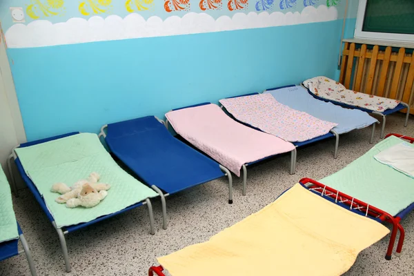 Bedden en babybedjes in felgekleurde slaapzaal van een kwekerij — Stockfoto