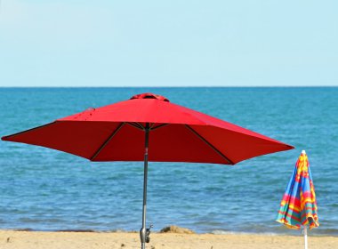 Kırmızı plaj şemsiye plaj ve mavi denizin üzerinde