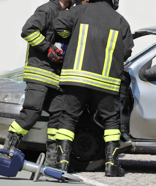 Dwóch Umundurowanych Strażaków Używa Potężnego Nożyc Hydraulicznych Otwarcia Samochodu Osobowego — Zdjęcie stockowe