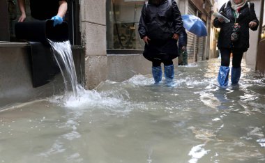 İtalya 'nın kuzeyindeki Venedik adasında biri, yüksek gelgitte dükkanın içinden kovayla suyu boşaltır.