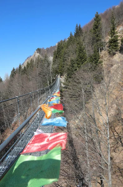 平和と祈りの多くのカラフルなチベットの旗のシンボルは 山の尾根の間のつり橋の重さ — ストック写真